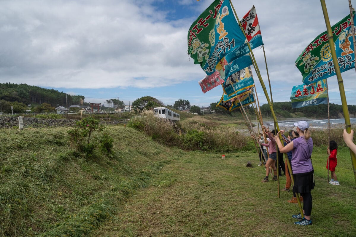 Participating in local tradition of waving flags at Hirono Emotion train